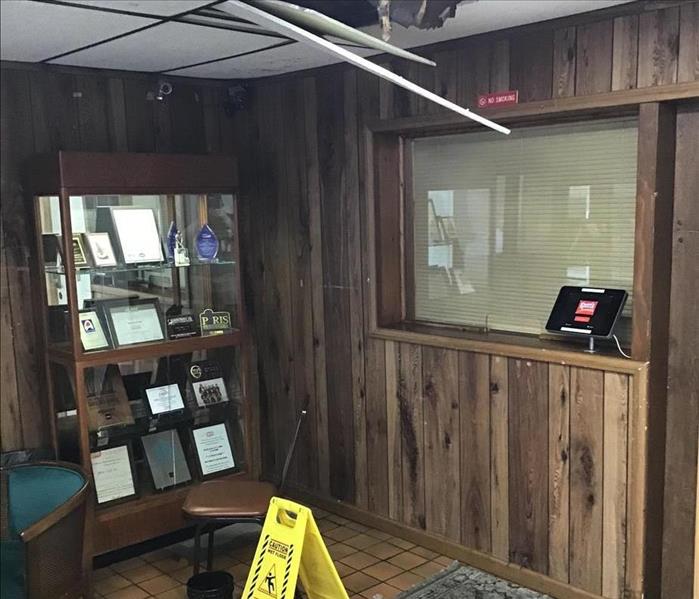 Photo of an office with visible damage to ceiling and floor.