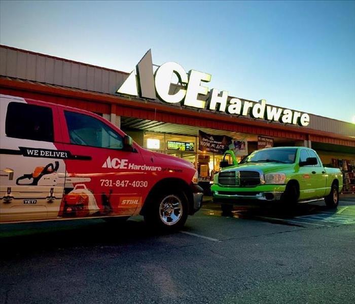 Ace Hardware sign with two vehicles parked in front of building